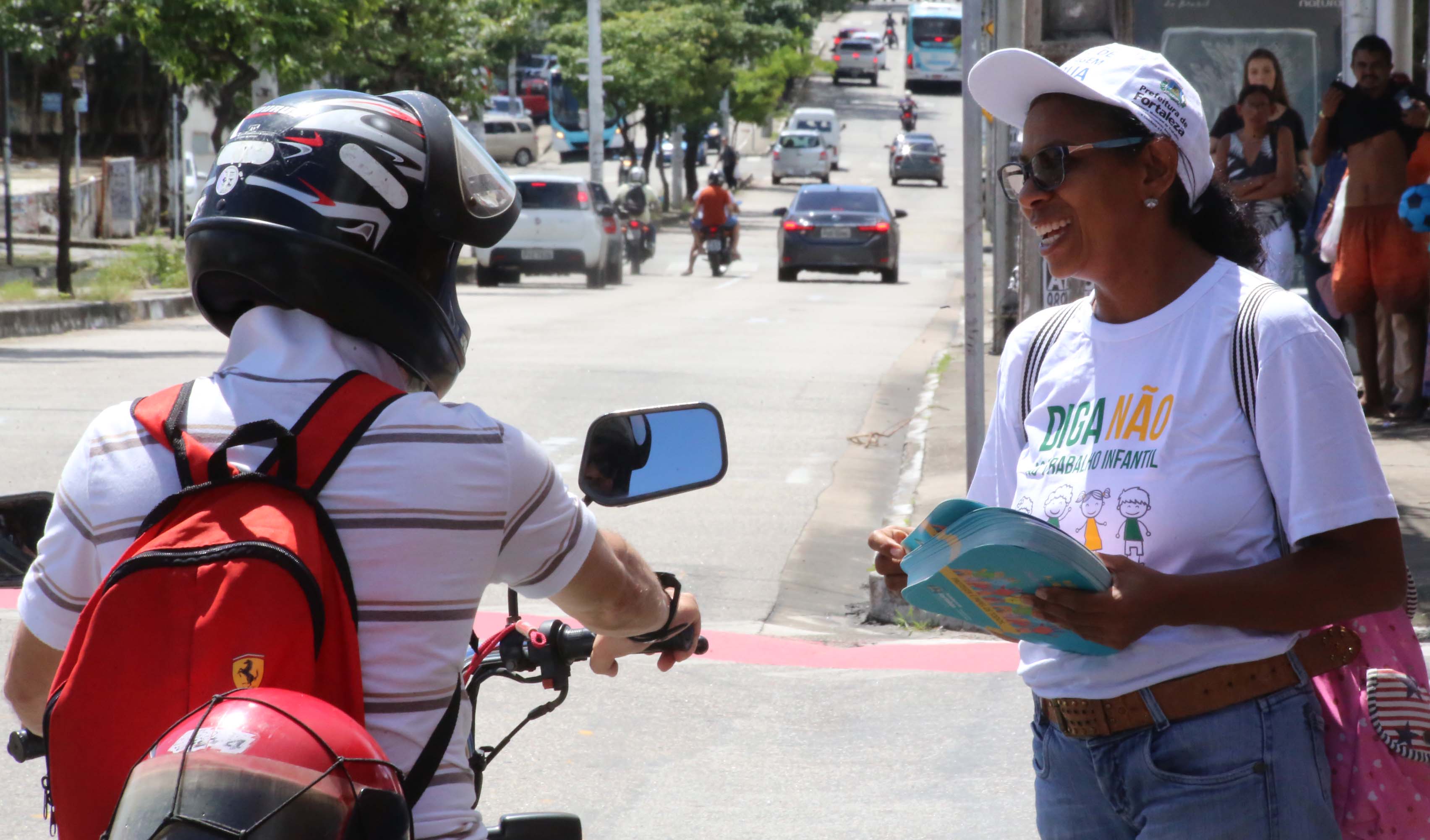 mulher aborda motoqueiro para entregar folder da campanha